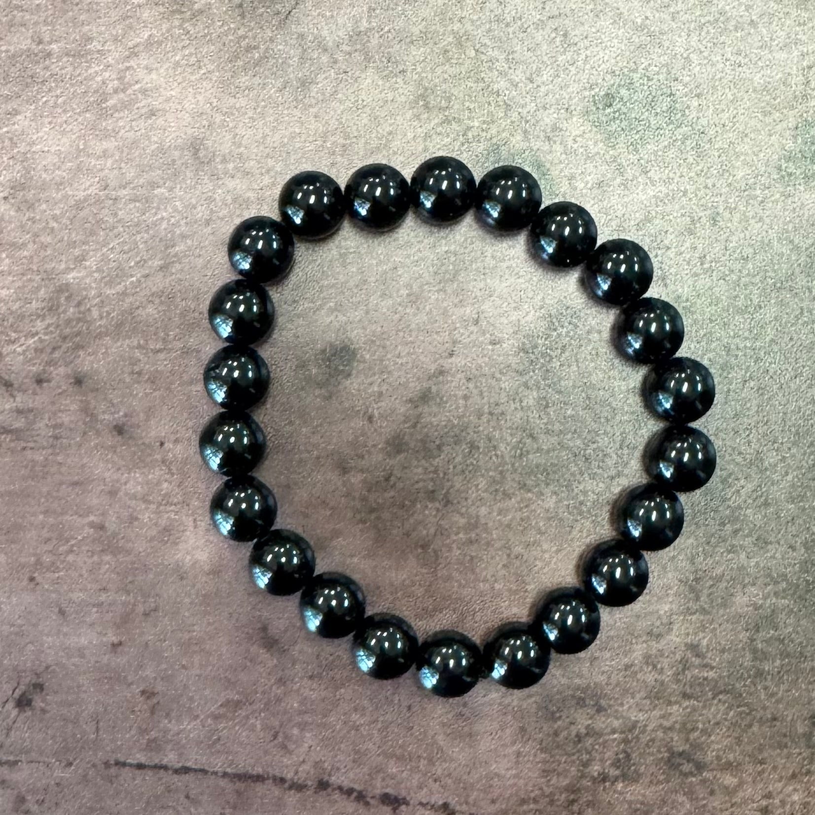 Black beaded bracelet on a textured gray surface