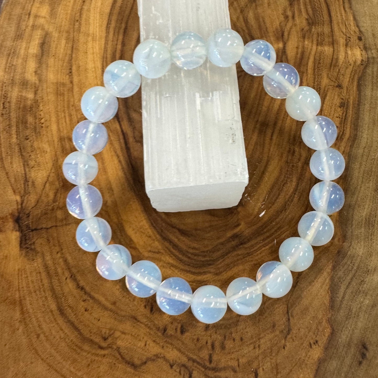 Opalite Beaded bracelet on a wooden surface with a crystal in the background