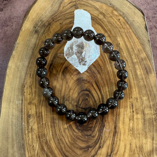 Black beaded bracelet on a wooden surface with a crystal