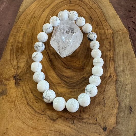 White beaded bracelet on a wooden surface with a crystal