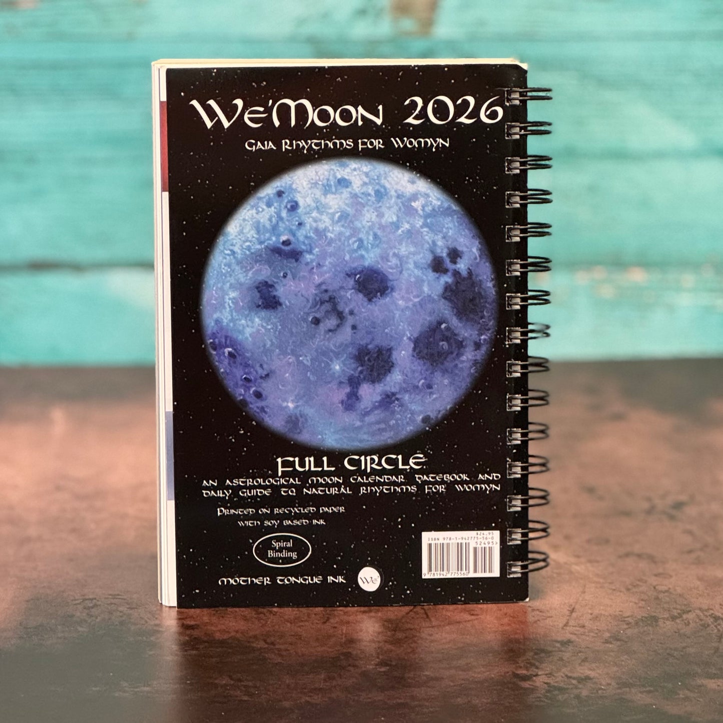 W'eMoon 2026 calendar with moon image on a wooden surface