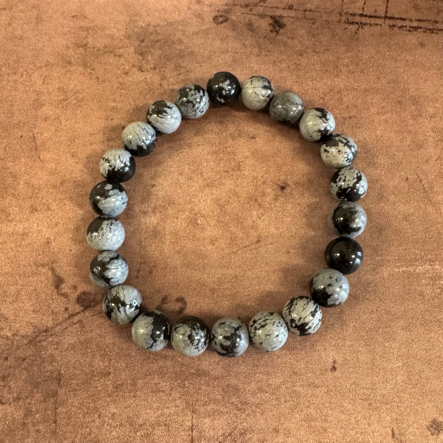 Beaded bracelet with black and gray beads on a brown textured background