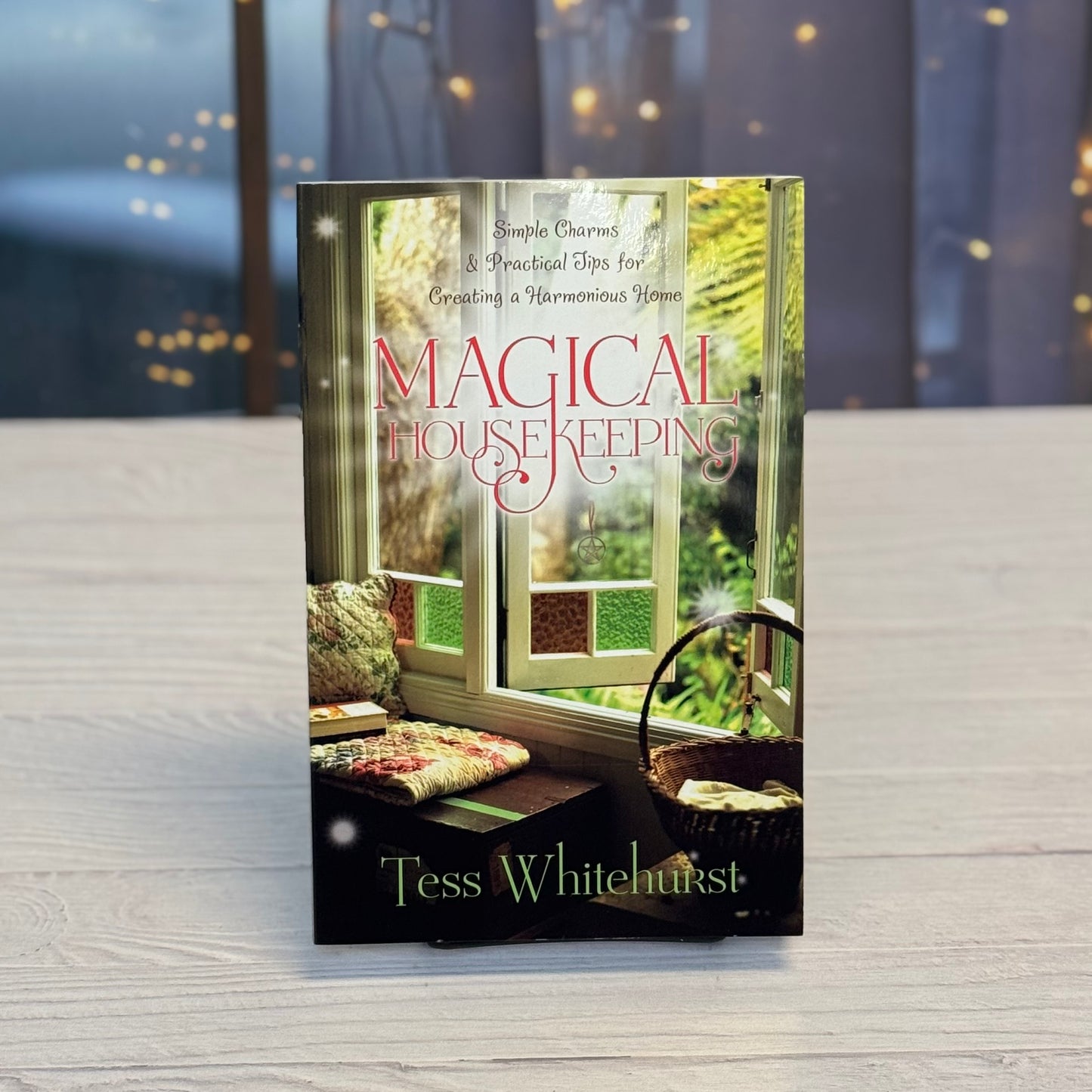 Book titled 'Magical Housekeeping' by Tess Whitehurst on a wooden surface with a blurred background