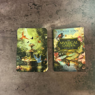 Two books titled 'The Mystical Garden Oracle' and 'Denise Linn' on a textured surface.