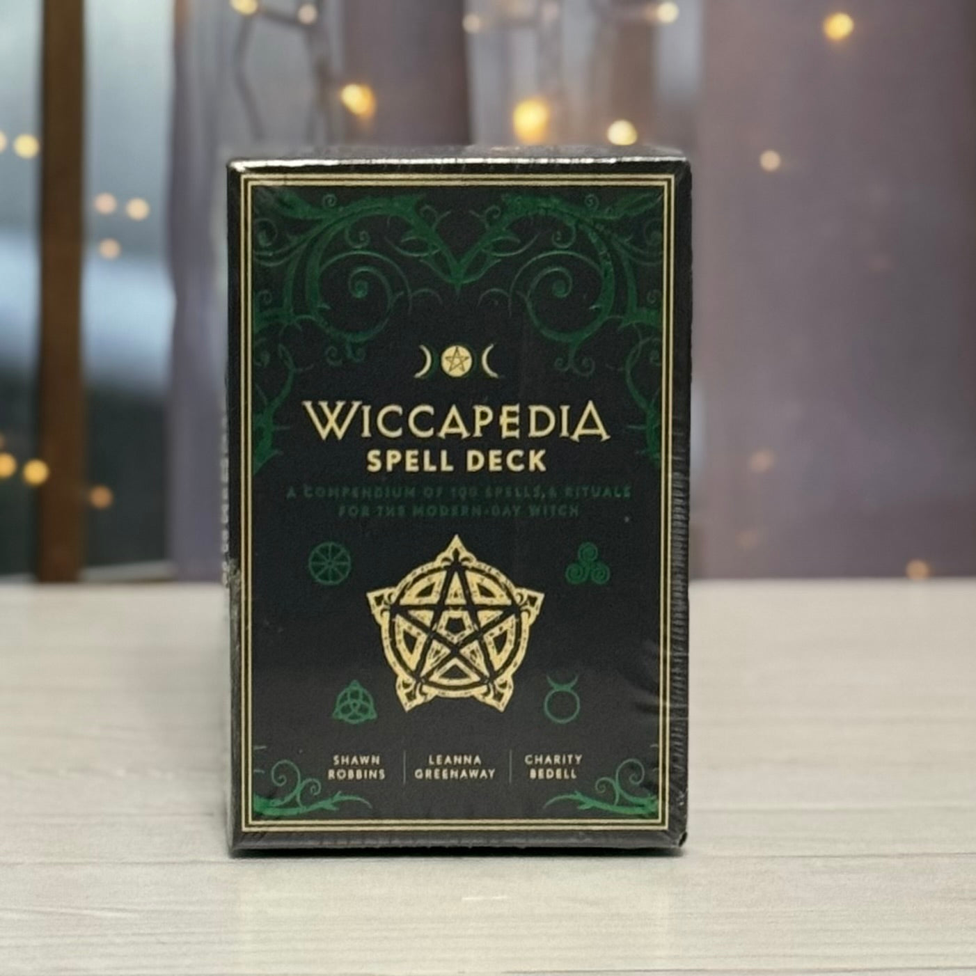 Wiccapedia Spell Deck packaging with decorative design on a blurred background