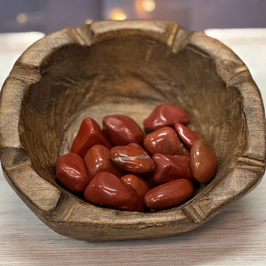 Wooden bowl with red stones on a light background