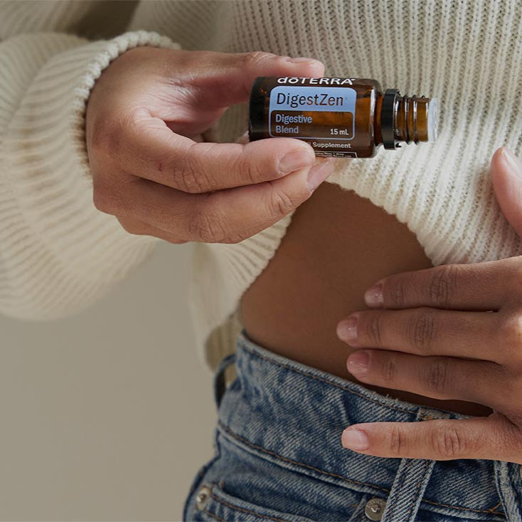 Person holding a bottle of doTERRA Essential Oil and a brown leather pouch against a neutral background