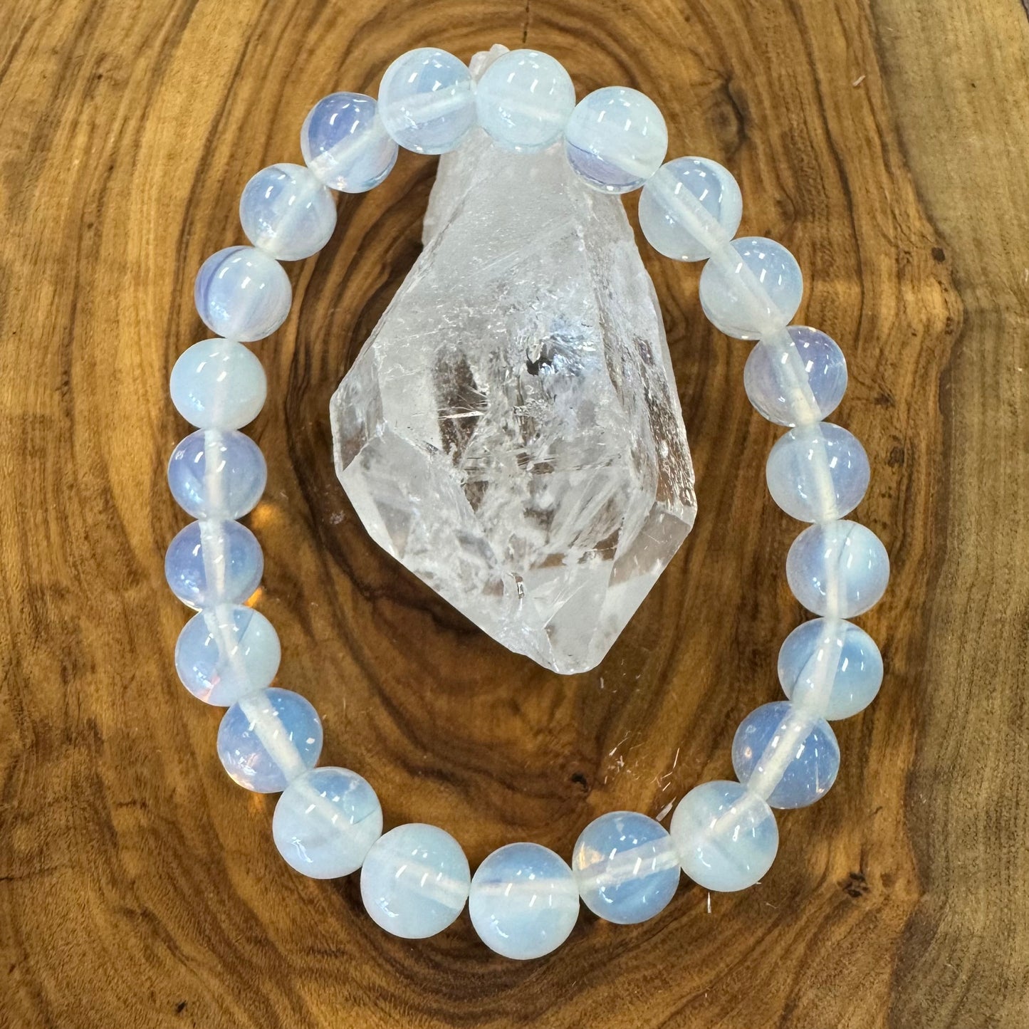 Opalite beaded bracelet on a wooden surface with a crystal rock
