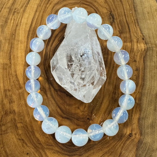 Opalite beaded bracelet on a wooden surface with a crystal rock