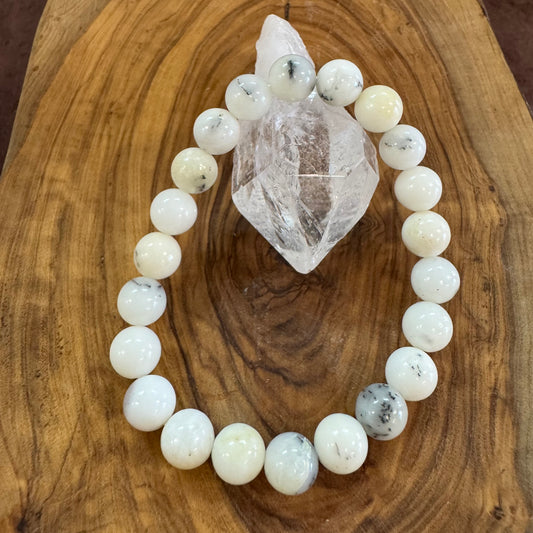 White beaded bracelet on a wooden surface with a crystal