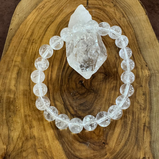 Clear beaded bracelet with a crystal on a wooden surface
