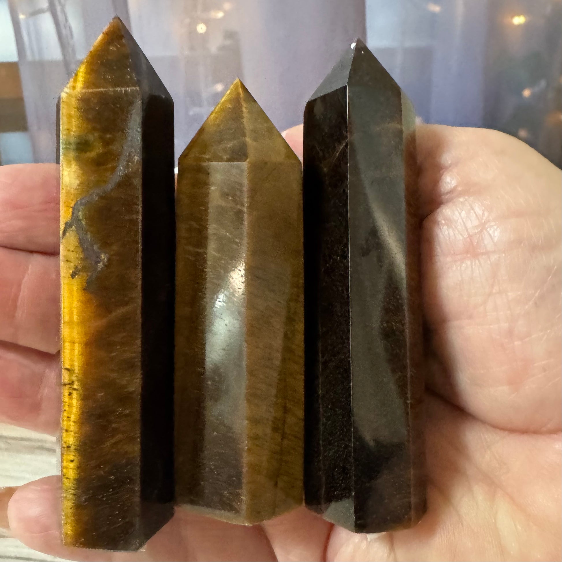 Three crystal points held in a hand with a blurred background