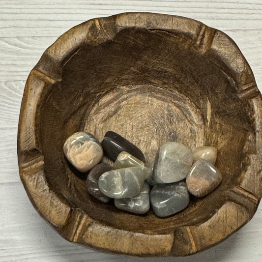 Wooden bowl with stones on a light wooden surface