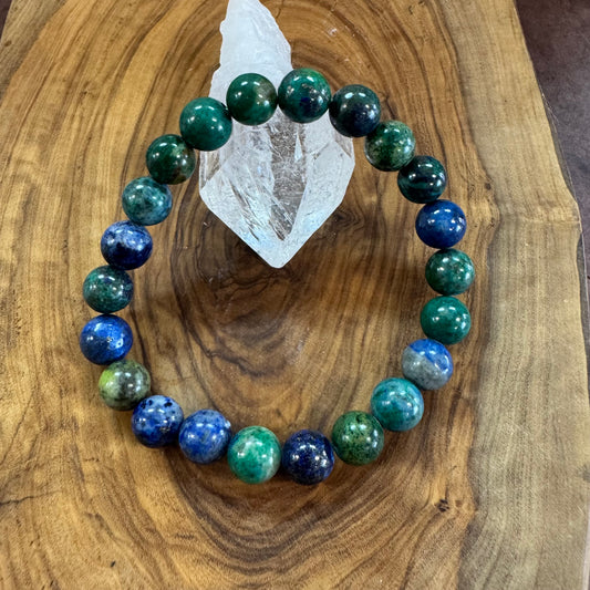 Multicolored beaded bracelet on a wooden surface with a crystal stone.