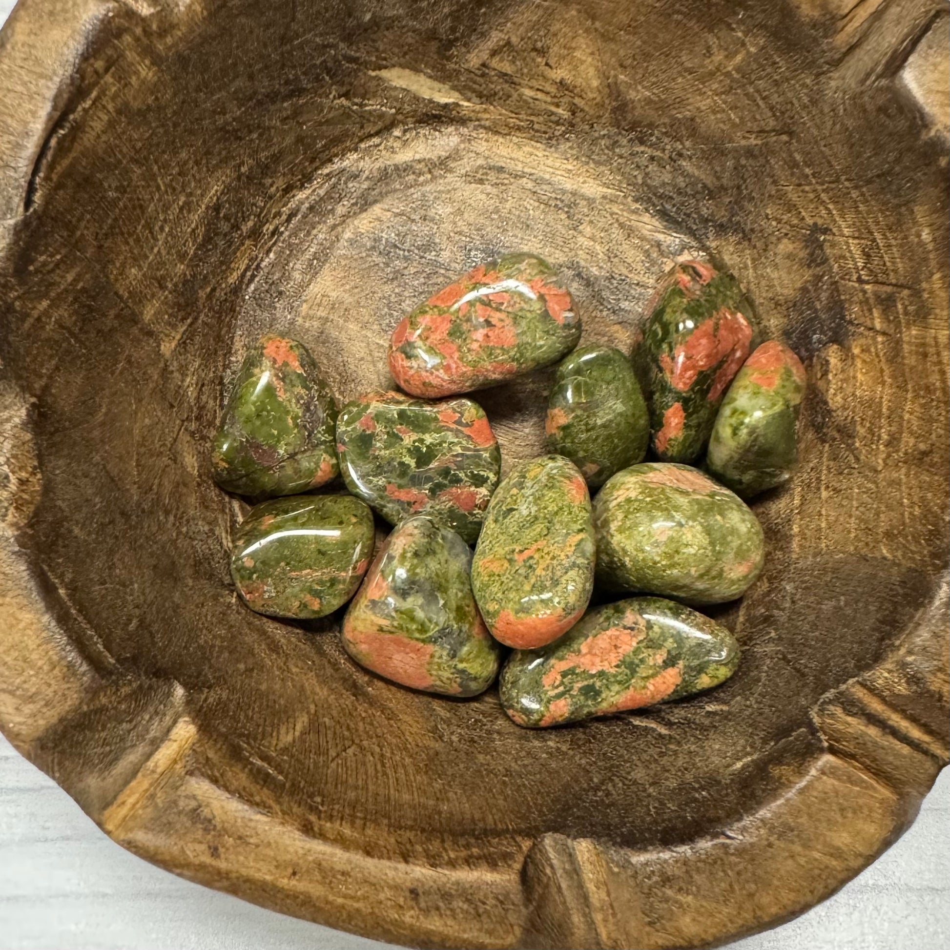 Green and red stones in a wooden bowl