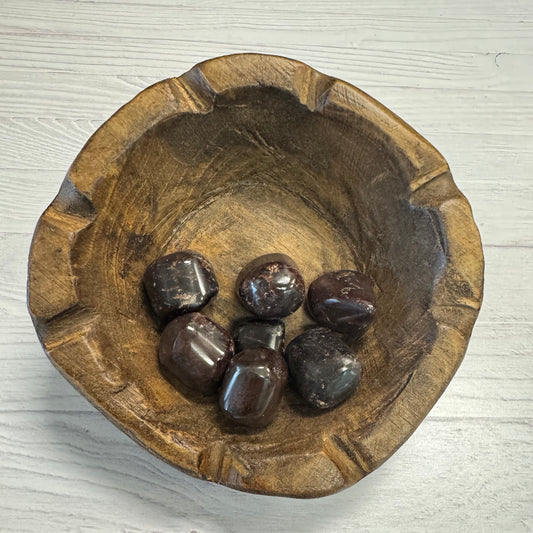 Wooden bowl with dark stones on a light wooden surface