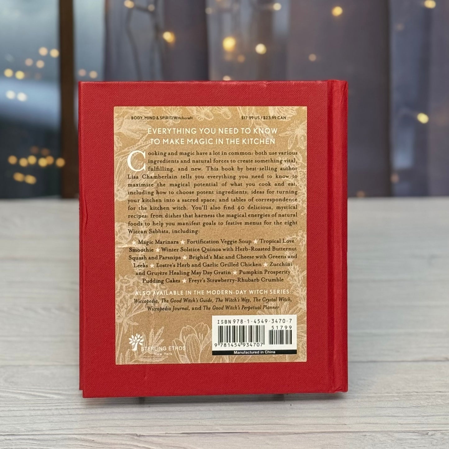 Back cover of a red book with text and a barcode on a wooden surface.