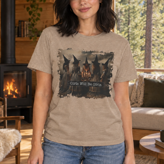 A woman wearing a beige graphic t-shirt with a distressed print of witches and the text 'Girls Will Be Girls.