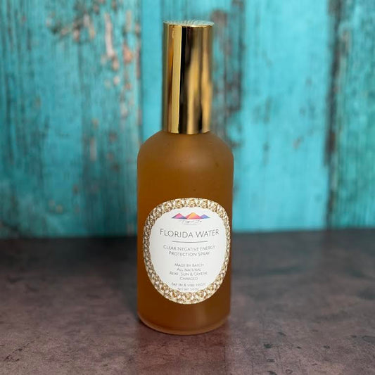 Bottle of Florida Water spray with a gold cap on a textured surface and blue background
