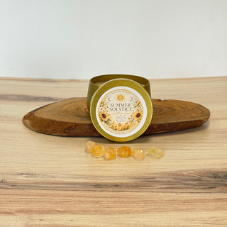 Gold tin labeled 'Summer Solstice' with sunflower design on a wooden surface