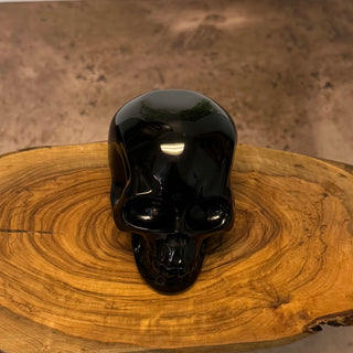 Black skull-shaped object on a wooden surface with a brown background