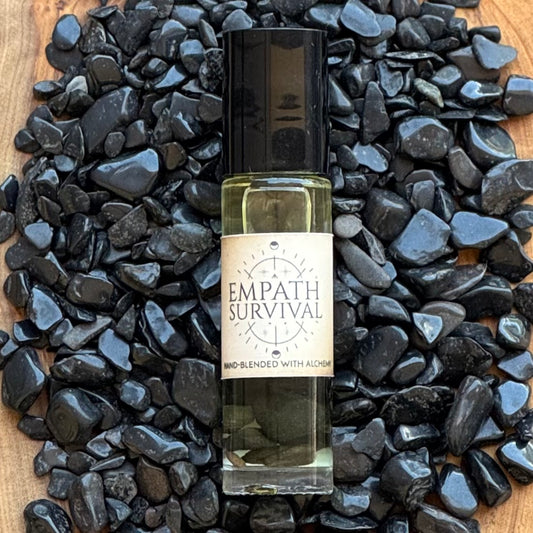 Bottle of 'Empath Survival' oil with a label on black pebbles