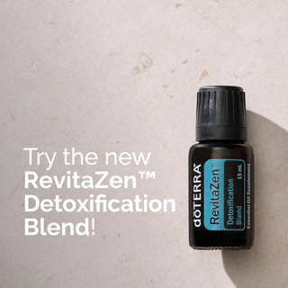 A small black bottle of doTERRA RevitaZen Detoxification Blend essential oil supplement placed on a light beige textured surface, with large white text on the left reading 'Try the new RevitaZen Detoxification Blend!'.