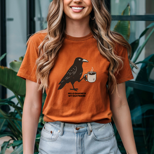 Woman wearing an orange t-shirt with a crow graphic and text, standing outdoors.