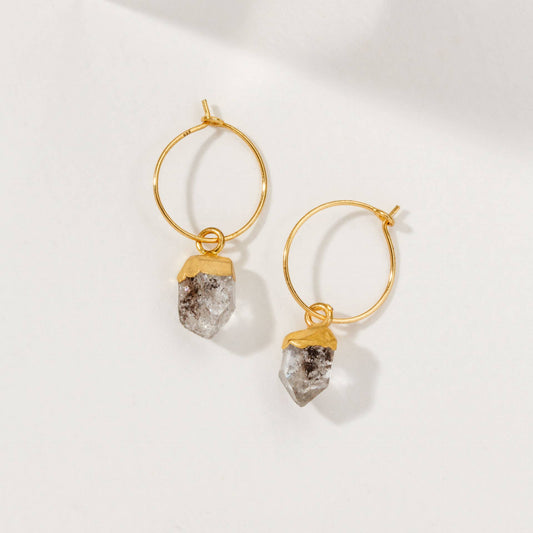 Gold hoop earrings with crystal-like attachments on a white background