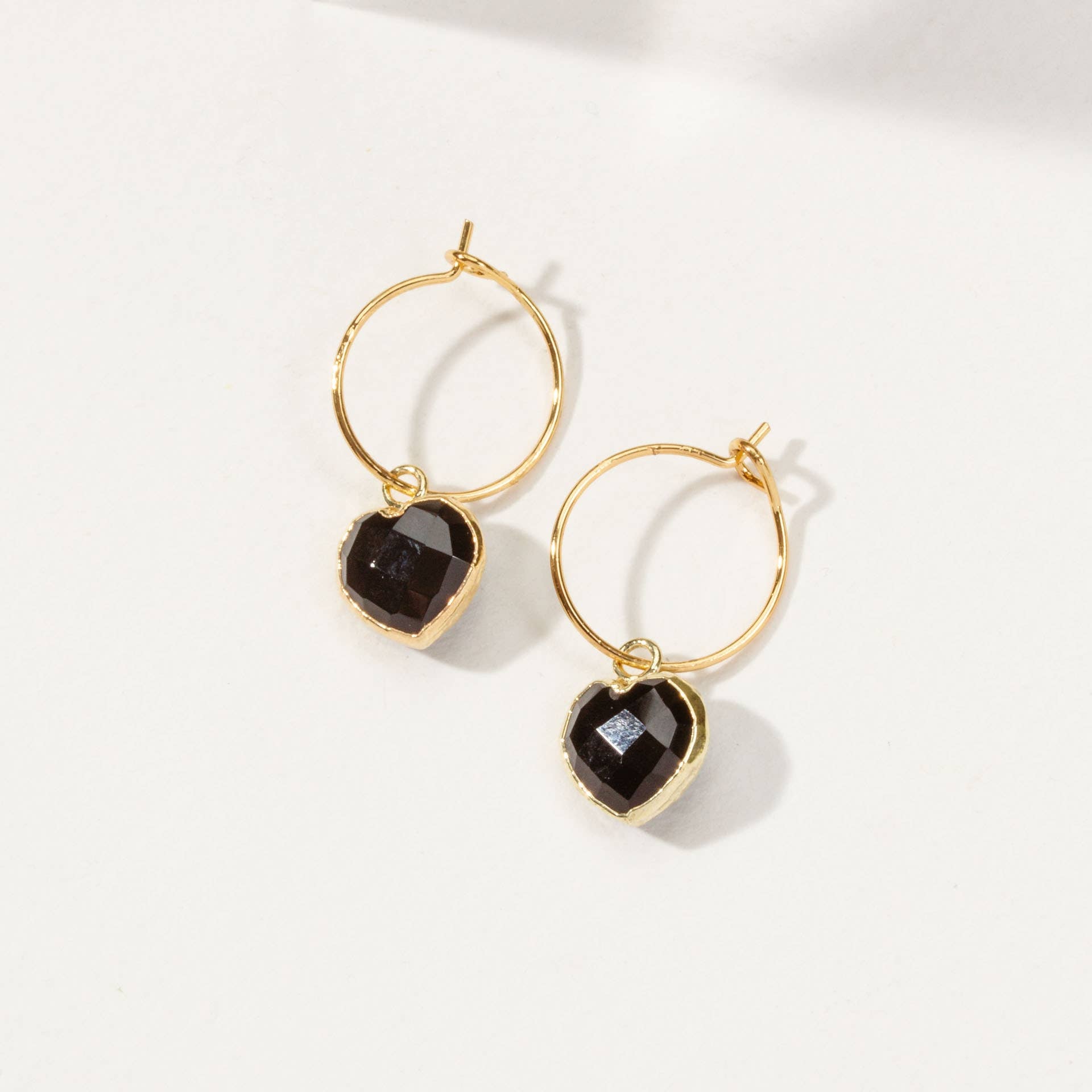 Gold hoop earrings with black gemstones on a white background