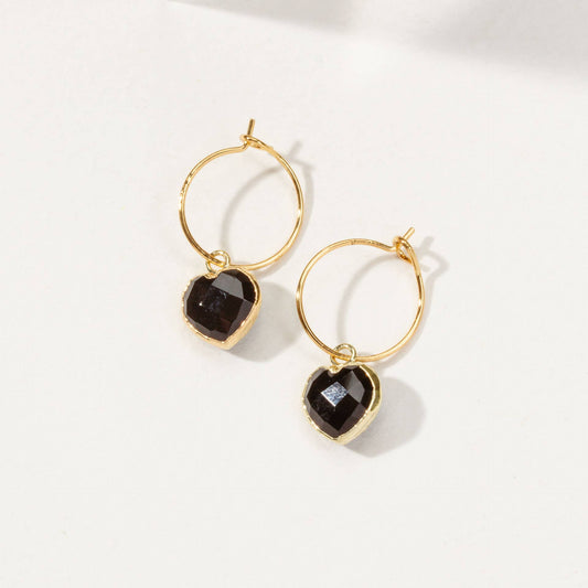 Gold hoop earrings with black gemstones on a white background