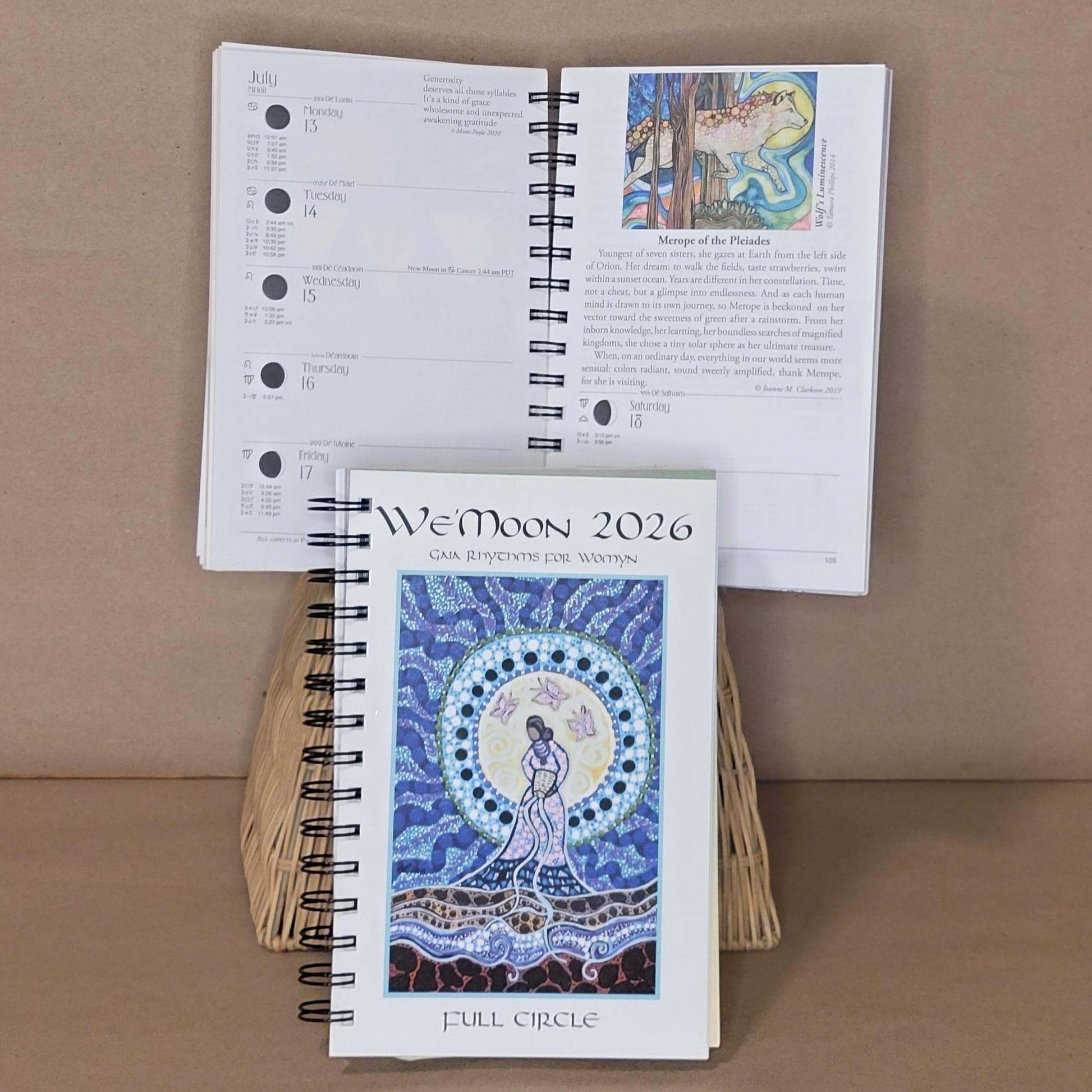 Spiral-bound planner with a cover featuring a woman and celestial design, on a brown background.