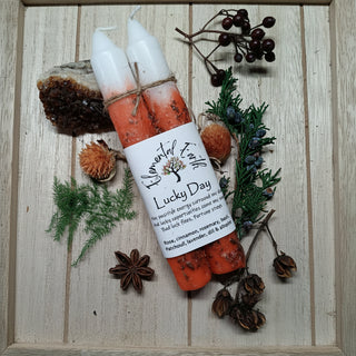 Two candles labeled 'Lucky Day' on a wooden surface with natural elements.