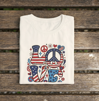 White Patriotic LOVE peace sign t-shirt folded on a wooden surface, colorful LOVE graphic with American flags