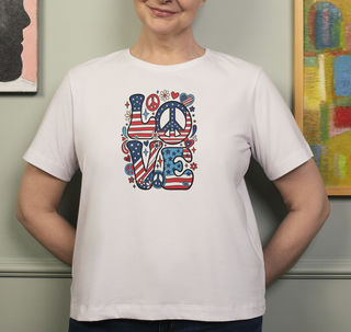 White Patriotic LOVE peace sign t-shirt worn by a person in front of framed artwork, colorful LOVE graphic