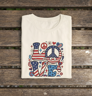 Natural Patriotic LOVE peace sign t-shirt folded on a wooden surface, colorful LOVE graphic with peace signs and flags