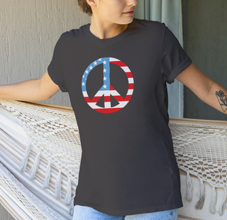 Dark grey heather American flag peace sign t-shirt worn by a person standing on a wooden deck