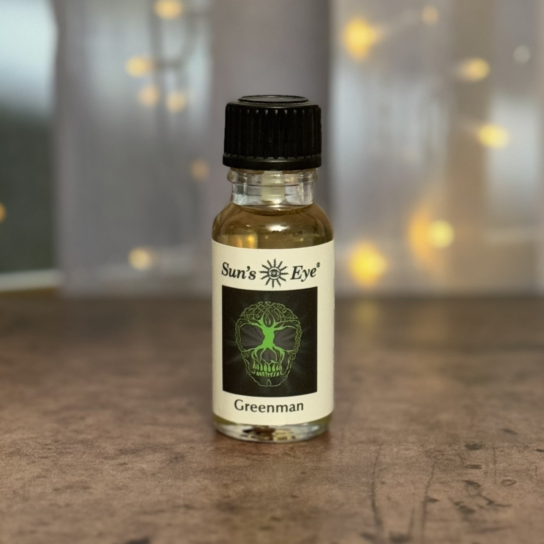 Bottle of 'Sun's Eye' Greenman oil on a wooden surface with a blurred background
