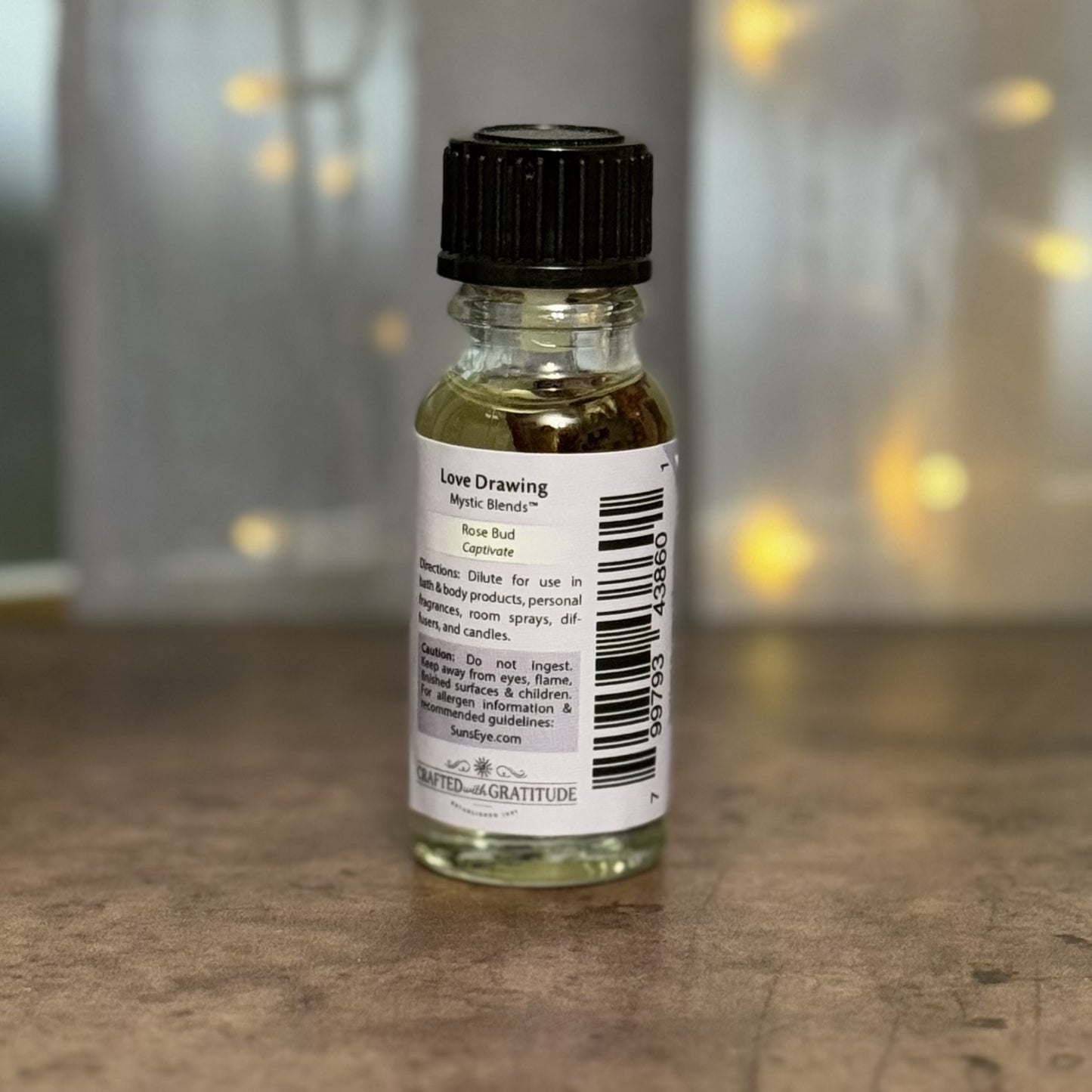 Small glass bottle with a black cap on a wooden surface, blurred lights in the background