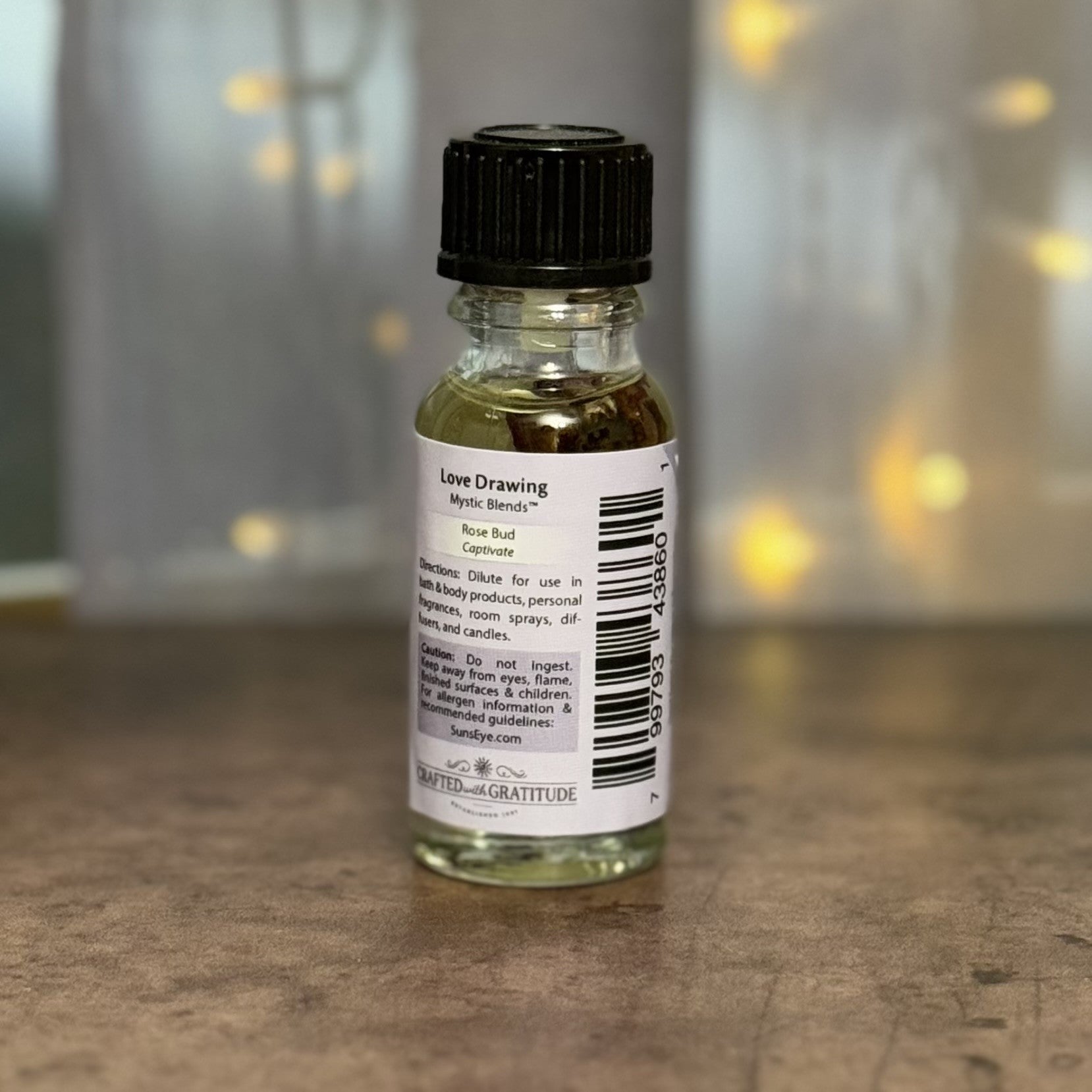 Small glass bottle with a black cap on a wooden surface, blurred lights in the background