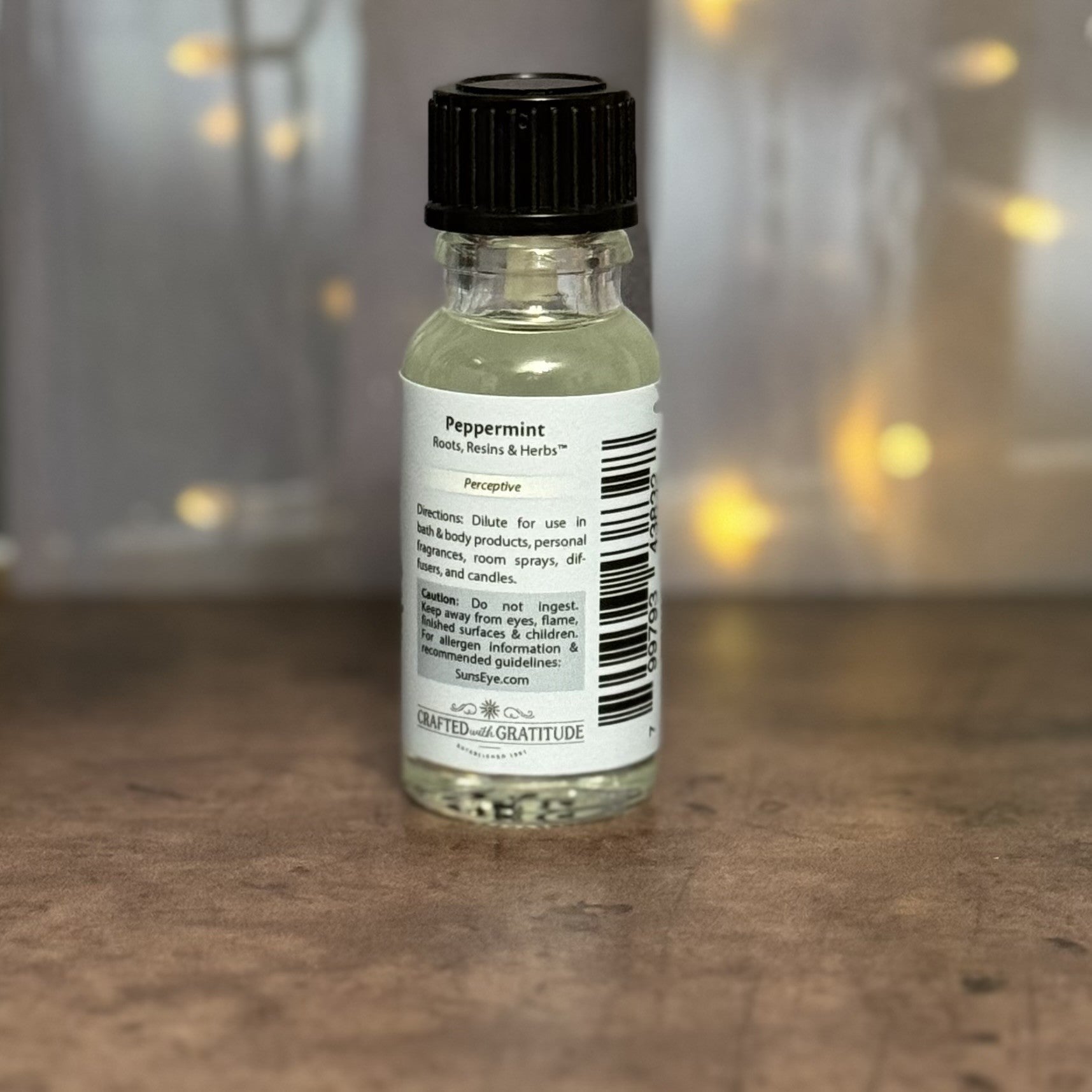 Small bottle with a black cap on a wooden surface, blurred lights in the background