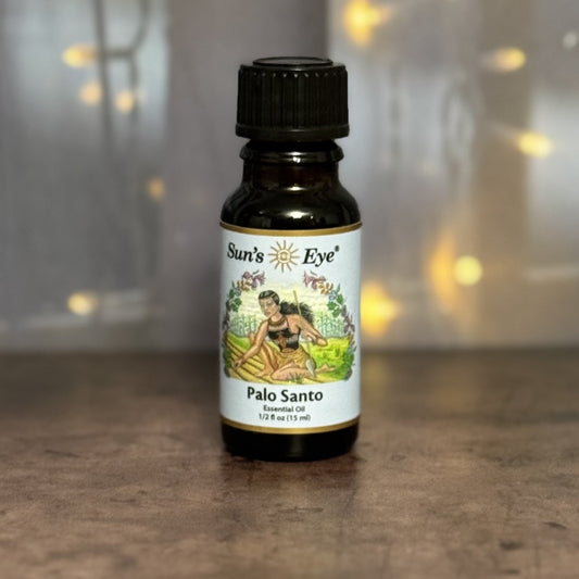 Sun's Eye Palo Santo essential oil bottle on a wooden surface with a blurred background