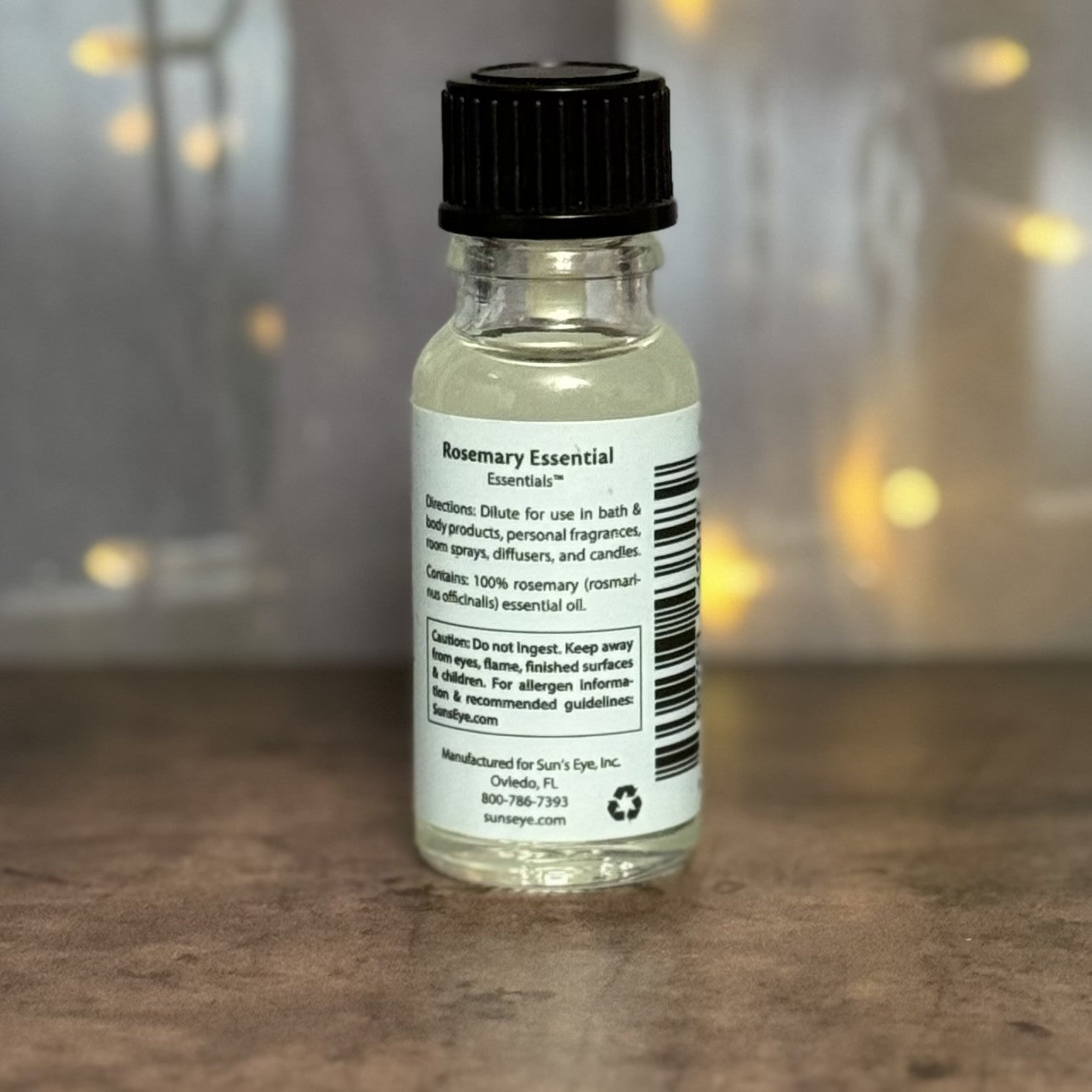 Bottle of Rosemary Essential Oil with label on a wooden surface