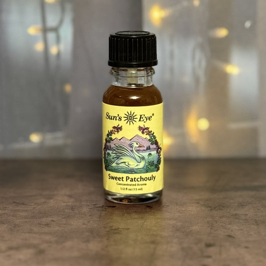 Bottle of Sun's Eye Sweet Patchouli oil on a wooden surface with a blurred background