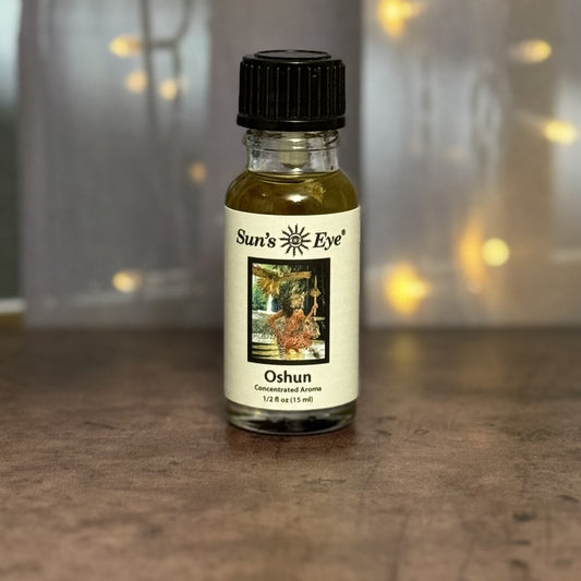 Bottle of Sun's Eye Oshun concentrated aroma on a wooden surface with a blurred background