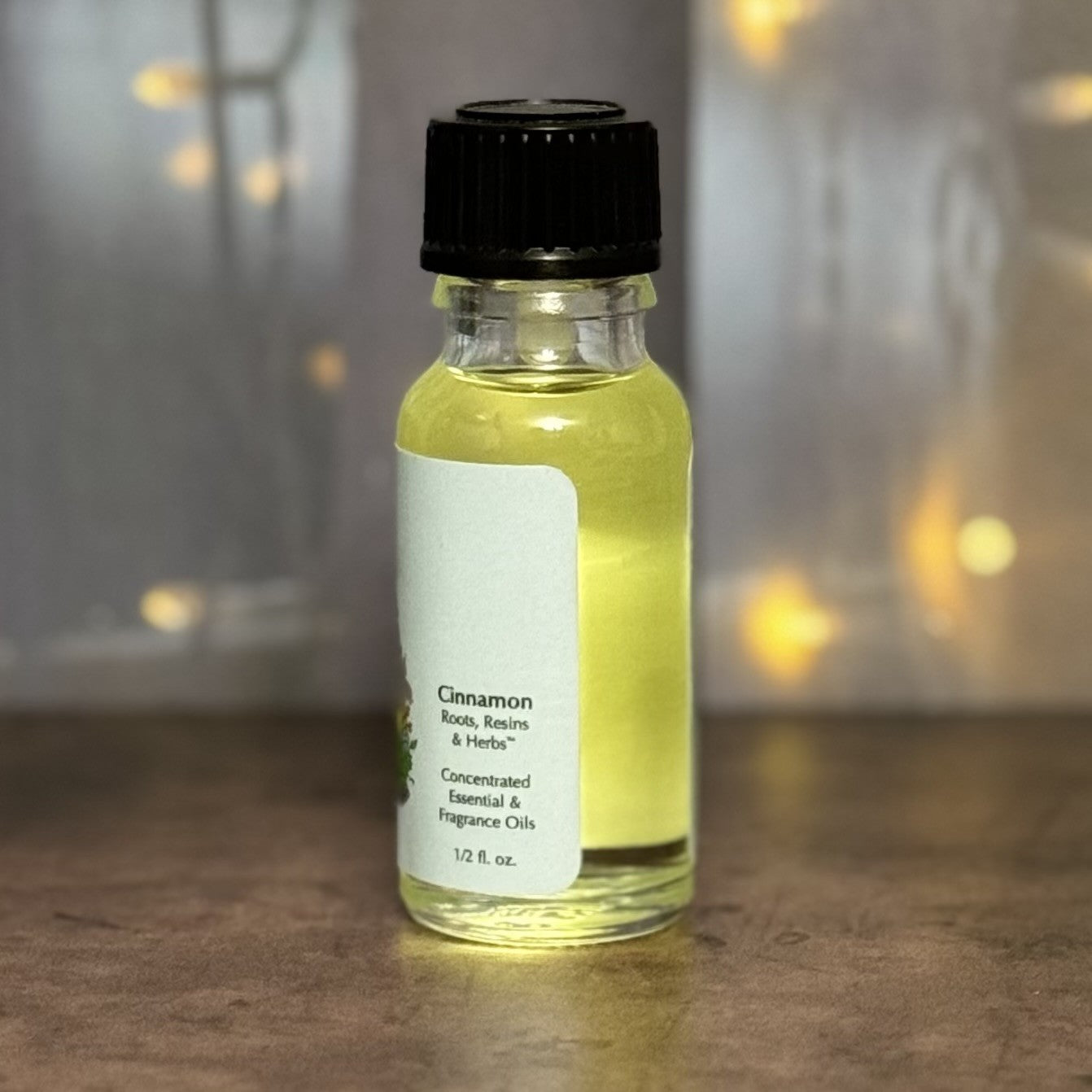 Small bottle of cinnamon essential oil with a black cap on a wooden surface.