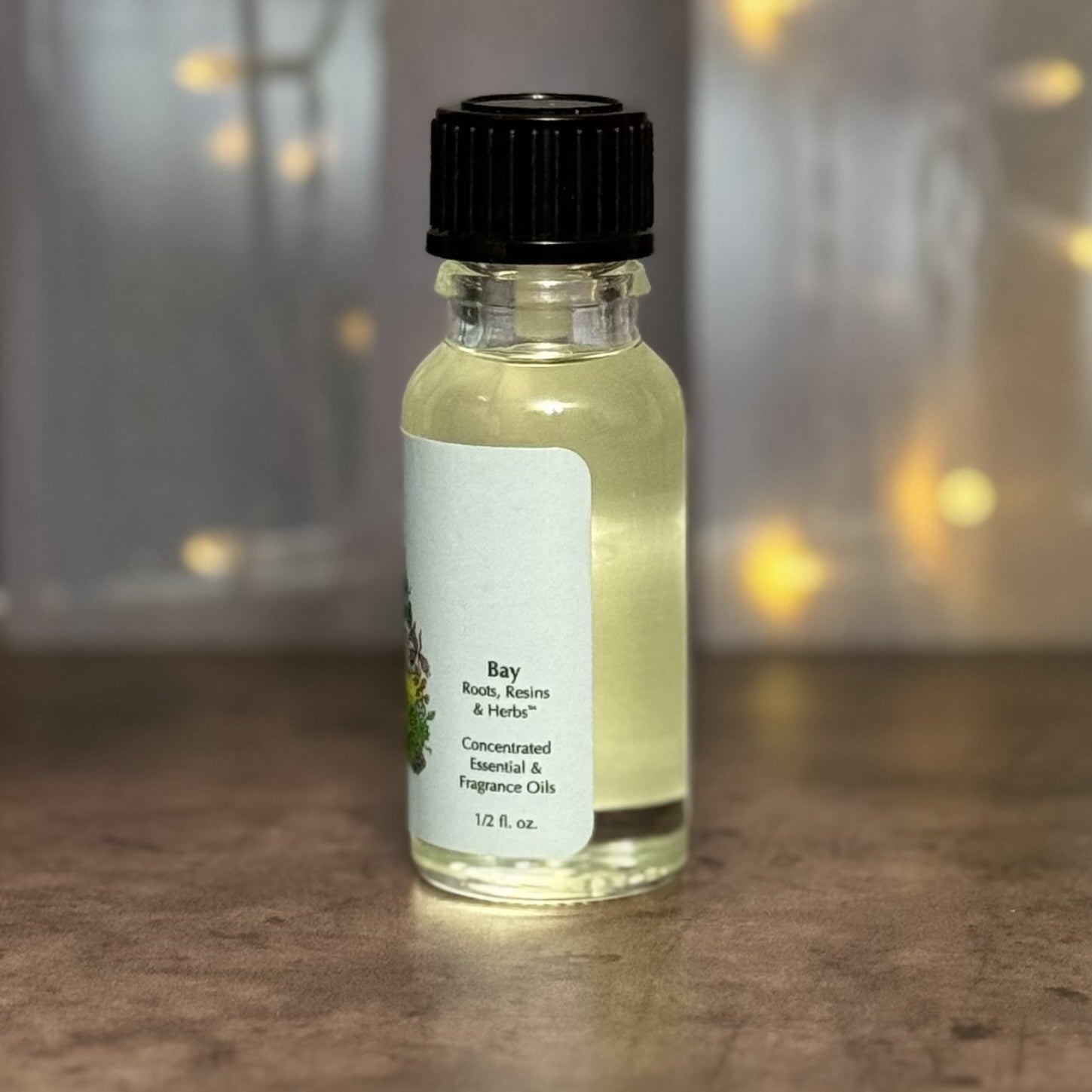 Small bottle of Bay essential oil with a black cap on a wooden surface.