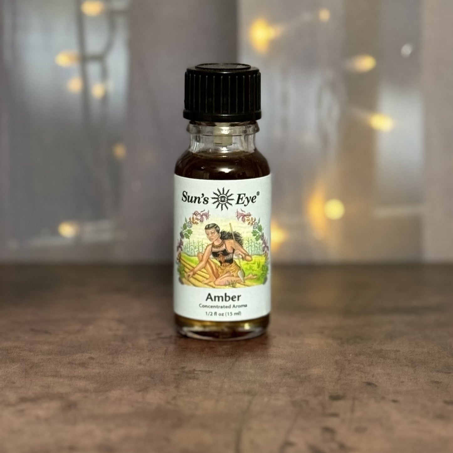 Bottle of Sun's Eye Amber concentrated aroma on a wooden surface with a blurred background