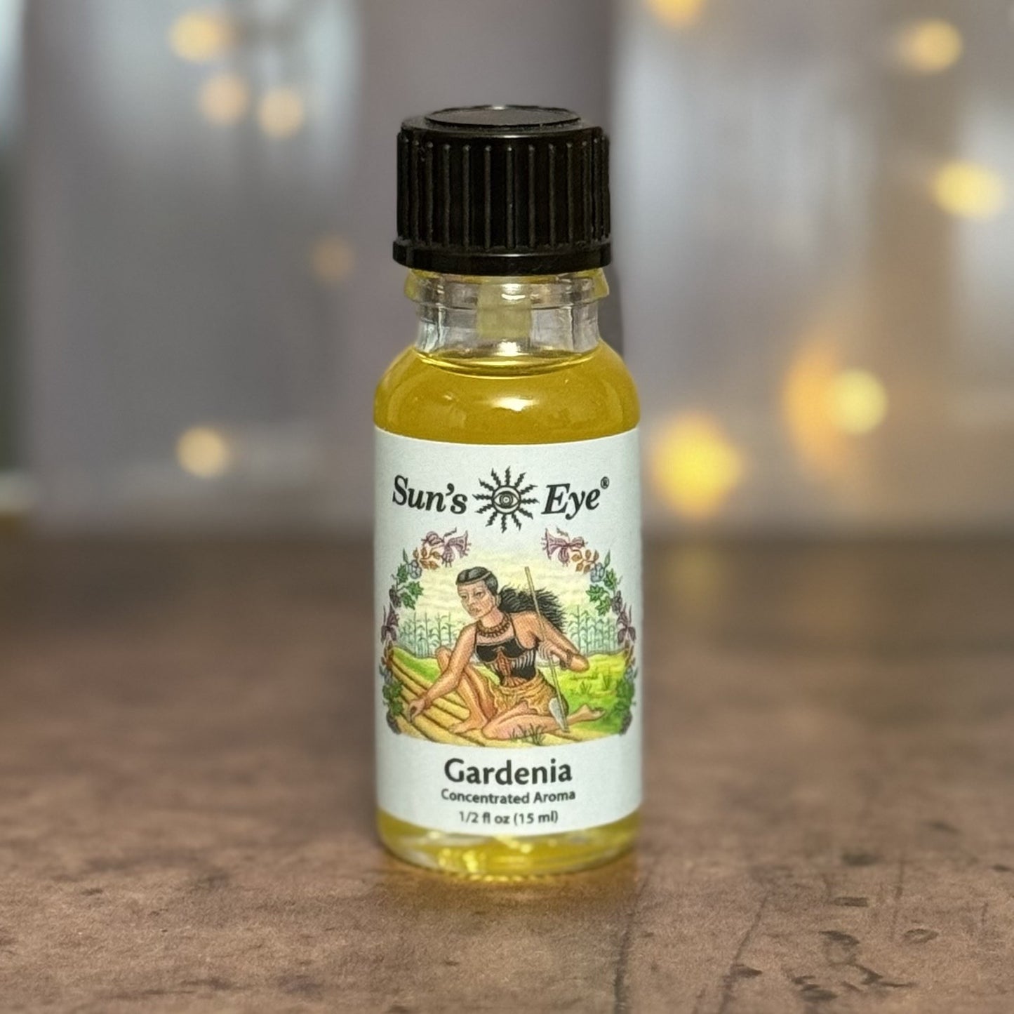 Bottle of Sun's Eye Gardenia essential oil on a wooden surface with a blurred background