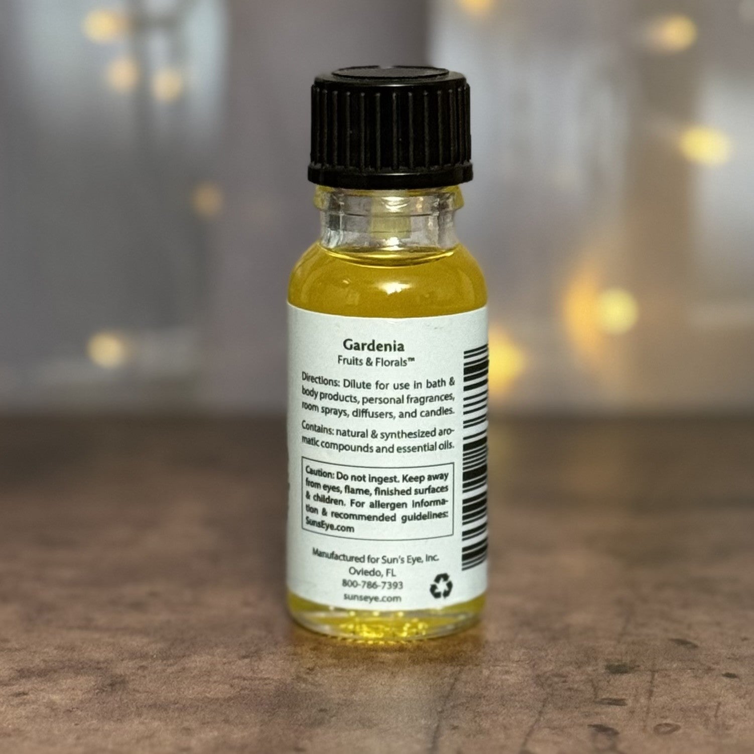 Small bottle of Gardenia essential oil with a black cap on a wooden surface.
